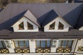 Close-up aerial view of building attic rooms exterior on metal shingle roof, stucco walls and plastic windows