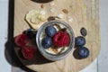 Close-up with aerial view of a glass jar with plain yogurt, blueberries, muesli and raspberries on a wooden board Royalty Free Stock Photo