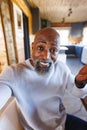 Close-up of african american bald confused senior man shrugging his shoulders in log cabin Royalty Free Stock Photo