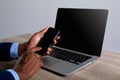 Close up of african american businessman using smartphone and laptop against grey background Royalty Free Stock Photo