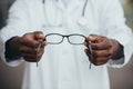 Close-up African American doctor offers glasses to patient, ophthalmologist sells glasses in store