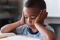 Close-up of african american elementary schoolboy reading book while sitting at desk in class Royalty Free Stock Photo