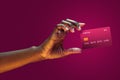 Close up african american female hand hold levitating mockup Bank credit card with online service on magenta background