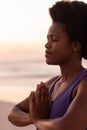 Close-up of african american mature woman with afro hair closing eyes and meditating at beach