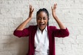 Close up African American Smiling Young Businesswoman making faces Wearing Jacket Looking at the Camera Against Gray Wall Royalty Free Stock Photo