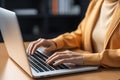 Close-up of African American womans hands typing on laptop in brightly colored modern office