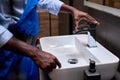 Close up of african black plumber& x27;s hand trying to open a water tap at bathroom Royalty Free Stock Photo