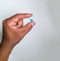 Close up on African male left hand holding a medicine capsule that's blue and white in color Royalty Free Stock Photo