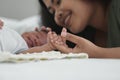 Close up of African new born baby holding mother`s finger while he is sleeping on bed. Young mom touch little infant boy`s head Royalty Free Stock Photo