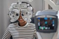 Close-up Of african teen girl Doing Eye Test On Phoropter, African teen girl checking on her eye with optometry machine