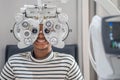 Close-up Of african teen girl Doing Eye Test On Phoropter, African teen girl checking on her eye with optometry machine Royalty Free Stock Photo