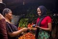 Close up of an african woman selling food stuff in a local african market holding a mobile point of sale device collecting a