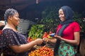 Close up of an african woman selling food stuff in a local african market holding a mobile point of sale device collecting a