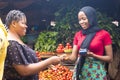 Close up of an african woman selling food stuff in a local african market holding a mobile point of sale device collecting a