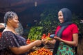 Close up of an african woman selling food stuff in a local african market holding a mobile point of sale device collecting a