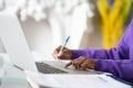 Close up of Afro-American woman employee or student using laptop, touches the touchpad with your finger, makes notes with pen Royalty Free Stock Photo