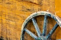 Close-up of age weathered wagon wheel with wooden spokes leaning against a yellow wooden box Royalty Free Stock Photo