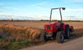 Close-up of agriculture red tractor cultivating field over blue sky Royalty Free Stock Photo