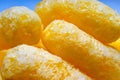 Close-up of Airy Crisps, Corn Puffs, Puffcorn Snacks on Blue Background. Crunchy Flavored Puffed Ready to Eat Treats. Party, Movie Royalty Free Stock Photo