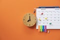 Close up of alarm clock and calendar on the orange table background