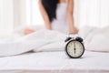 Close up of alarm clock at 6 o`clock in the morning and blurred woman waking up in her bedroom Royalty Free Stock Photo