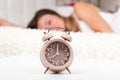 Close-up of an alarm clock on the table in the bedroom. Woman sleeping in the background, selective focus. copy space