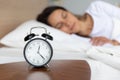Close up alarm clock on bedside table, peaceful woman sleeping Royalty Free Stock Photo