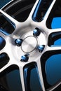 close-up of an alloy wheel and blue wheel nuts on a gradient blue background. aluminum wheel details, beautiful shiny