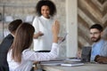 Close up ambitious female employee raise hand ask question.