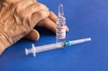 Close-up of an ampoule with the Covid-19 coronavirus vaccine and a syringe of the hand of an elderly man. The topic of vaccination