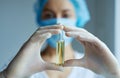 Close-up ampule with liquid drug in hands in gloves. doctor or scientist in laboratory blurred on background.