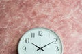 Analog vintage white clock on pink cement wall background.