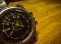 A close up Analog watch of silver metallic with wooden background