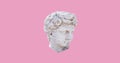 Close up of ancient sculpture male head and copy space on pink background
