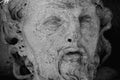 Close up ancient statue of Sisyphus face. God Zeus punished Sisyphus: he had to roll very big stone to top of high mountain rock,