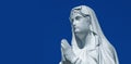 Close up ancient statue of the Virgin Mary praying against blue background of sky Royalty Free Stock Photo