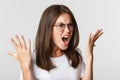 Close-up of angry and outraged beautiful woman in glasses yelling and shaking hands, having an argument