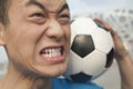 Close up of angry young man holding a soccer ball Royalty Free Stock Photo