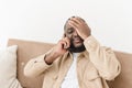 Close-up of an annoyed African American young man sitting on a couch talking on a cell phone. Angry black young man Royalty Free Stock Photo