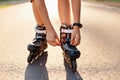 Close-up of an anonymous kid`s hands fixing laces on roller blades before skating, unknown child on road in sunny summer day, Royalty Free Stock Photo