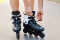 Close-up of an anonymous woman hands fixing laces on roller blades during skating, unknown female on road in summer park, Royalty Free Stock Photo