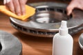 Close-up on an anti-rust spray and man cleaning a brake rotor in the background