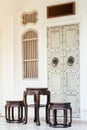 Close up antique chinese traditional chairs and table with white Chino-Portuguese door background. Asia architecture vintage style Royalty Free Stock Photo