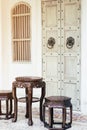 Close up antique chinese traditional chairs and table with white Chino-Portuguese door background. Asia architecture vintage style Royalty Free Stock Photo