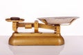 Close up of antique gold painted weighing scales with weight on left side on white background. Royalty Free Stock Photo