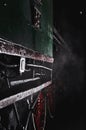 Close-up of an antique green railway car with red wheels, dim light in darkness, earthy night climate