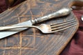 Close up of antique silver fork and knife with aged cutting board with on wooden background