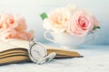 Close up of antique silver pocket watch and opened book with rose flowers on white and blue background with vintage tone Royalty Free Stock Photo