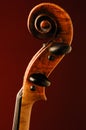 Close up of antique violin scroll on dark red background