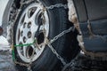 Close-up of antislip chain on car wheel with friction tire. Bottom perspective. The concept of safety on snowy roads.